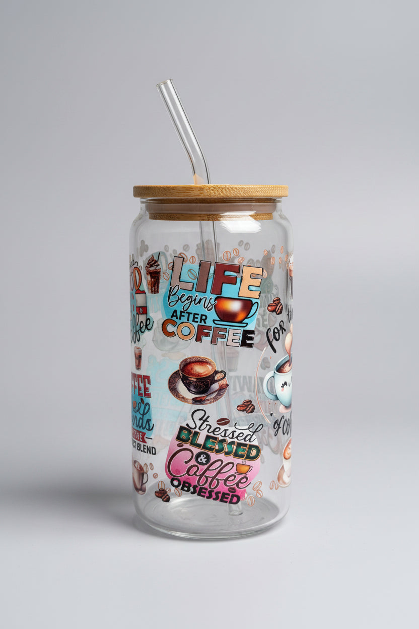 Glass tumbler with coffee-themed design and text on a wooden surface outdoors.