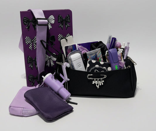 A purple and black notebook with pencil pouch and stationary set containing stationary items with a double wristlet