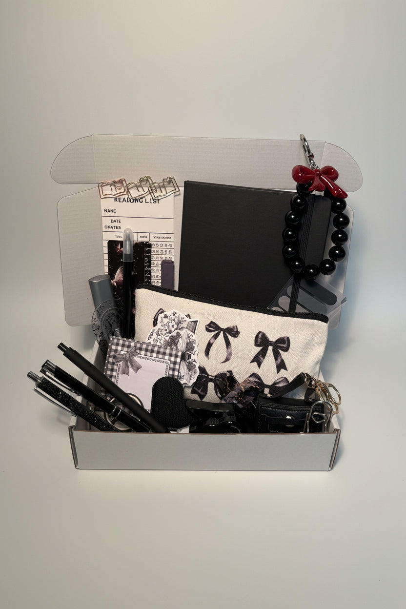 Collection of black stationary items including journal, pencil bag, pens, charms