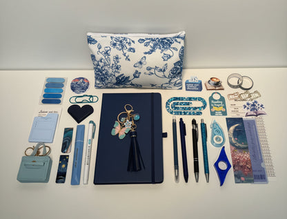 blue Stationery items including pens, notebooks, and decorative elements on a white surface with storage drawers in the background.