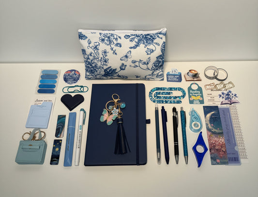 blue Stationery items including pens, notebooks, and decorative elements on a white surface with storage drawers in the background.