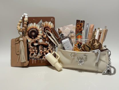 A beige and brown stationery and accessory organizer set displayed on a white surface in front of clear plastic storage drawers filled with colorful pens and supplies. The set includes a floral notebook, a tan wallet with a tassel, a cream pouch, and various matching stationery items.