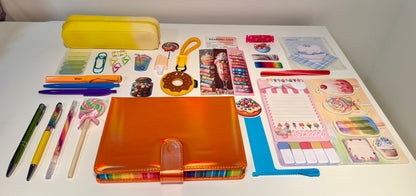Assorted stationery items including pens, notebooks, and decorative items on a white surface.