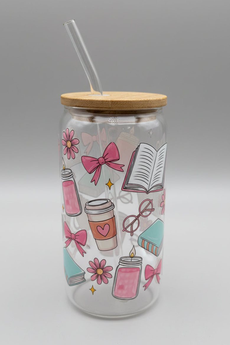 Glass tumbler with a lid and straw featuring colorful illustrations on a cardboard background