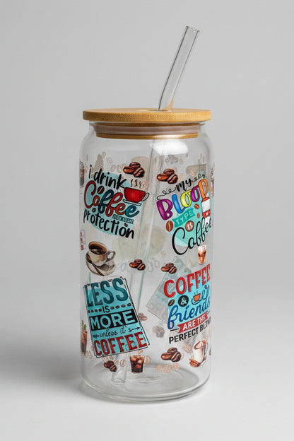 Glass tumbler with coffee-themed designs and text on a wooden surface outdoors.