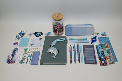 Collection of ocean theme stationery items and a cup  on a table with drawers in the background