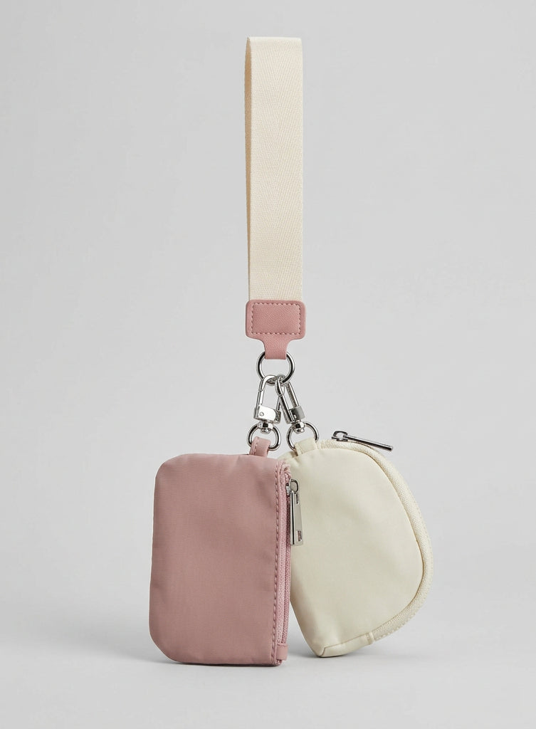A small zippered pouch set on a white surface, featuring a dusty pink fabric card holder with a cream strap and a cream zippered coin pouch attached by silver metal clips.