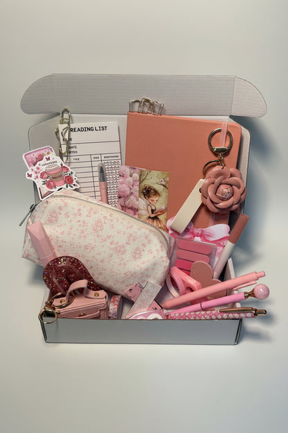 Collection of pink stationery items including a pouch, pens, and keychains on a desk.