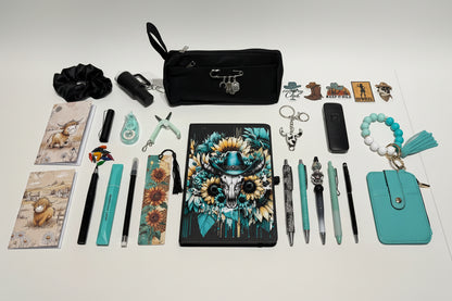 A curated flat-lay of various stationery and lifestyle accessories arranged on a white table in front of a white organizer drawer unit. The central focus is a black tablet case decorated with a colorful skull wearing a sunflower hat.